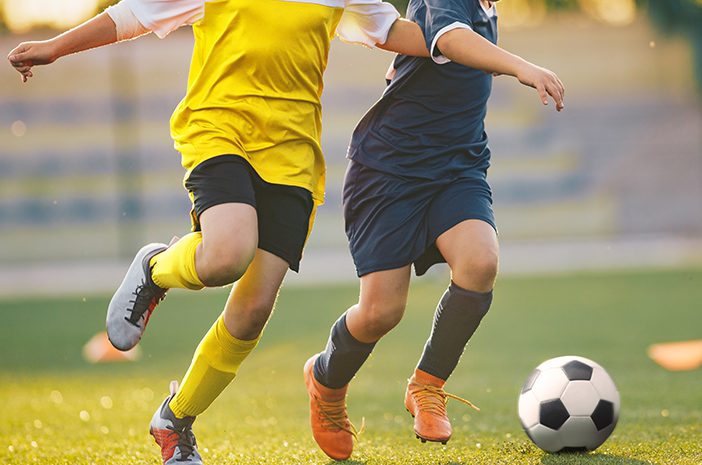Two,Soccer,Players,In,A,Duel,On,Grass,Venue.,Boys